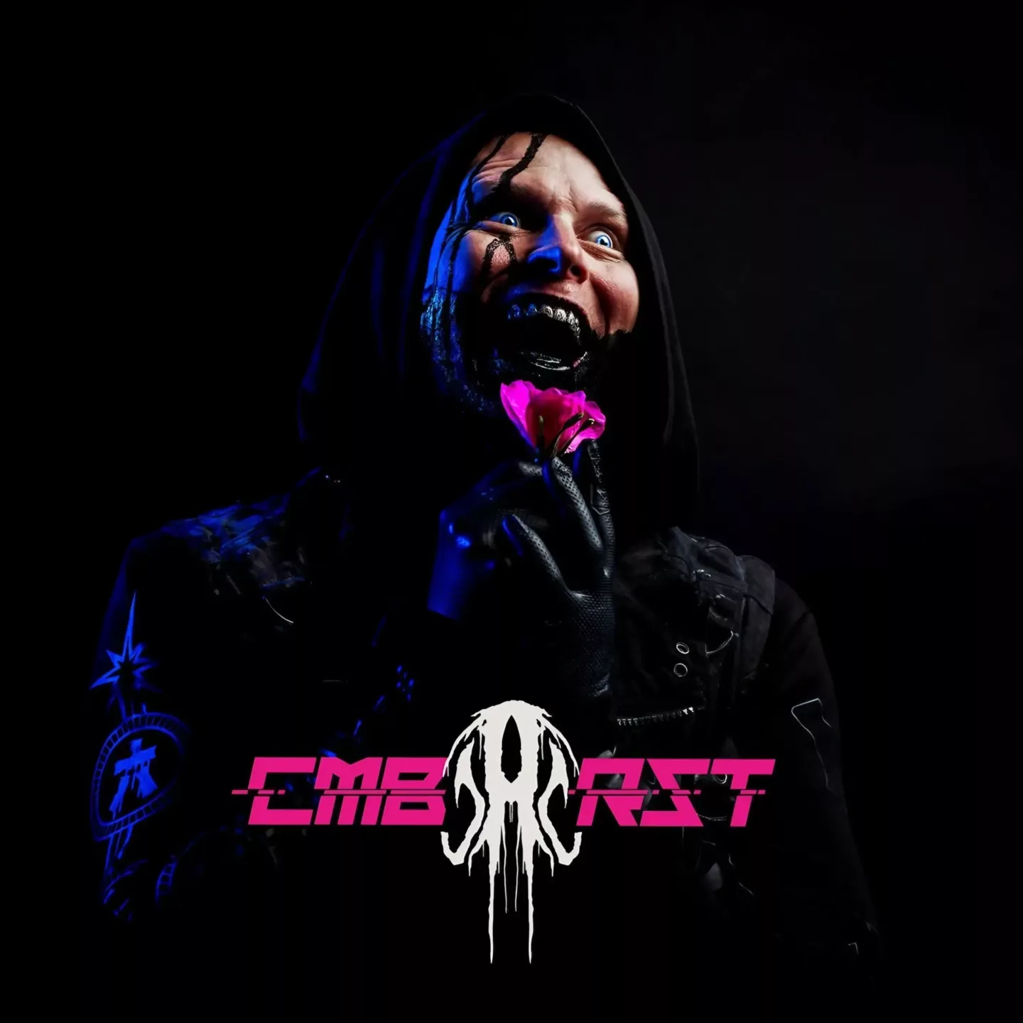 A hooded figure with black makeup and a wide grin holds a pink flower. The figure is lit with blue and pink lights.