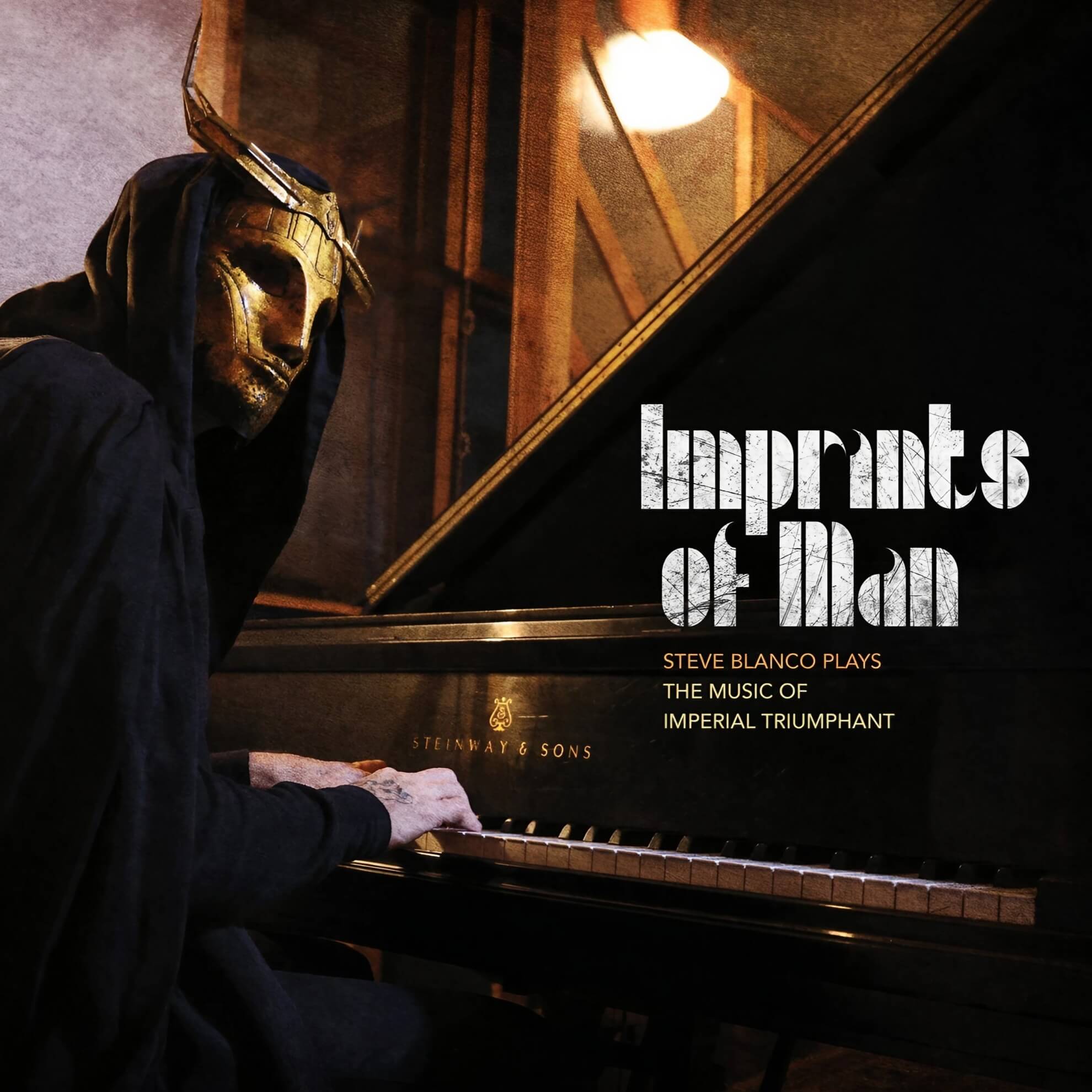 Steve Blanco, wearing a golden mask and black hood, plays a grand piano.
