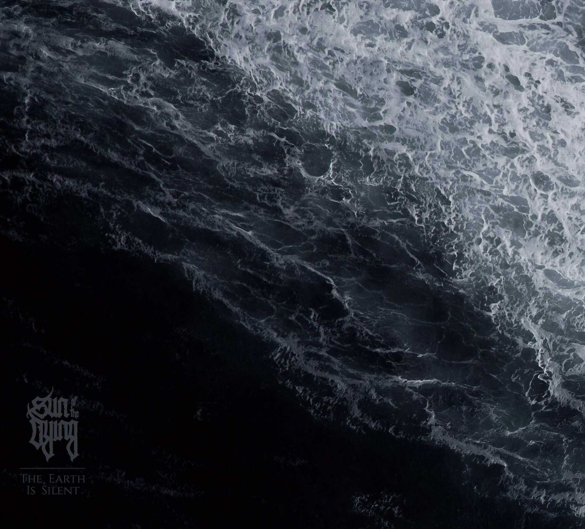 The album cover for ‘The Earth Is Silent.’ A monochromatic, high-contrast, top-down view of dark, turbulent water with white foam. The band’s logo and album title are in the lower-left corner.