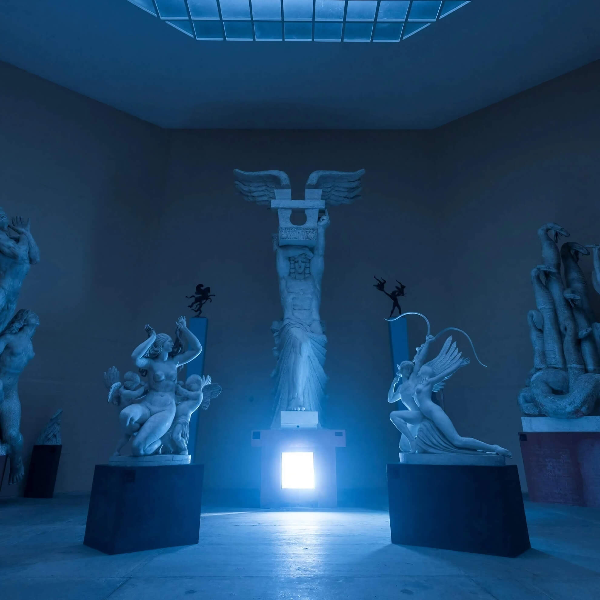 Album cover for ‘Age Of Aquarius.’ White statues stand in a dark room, bathed in cool blue light from a central glowing box.