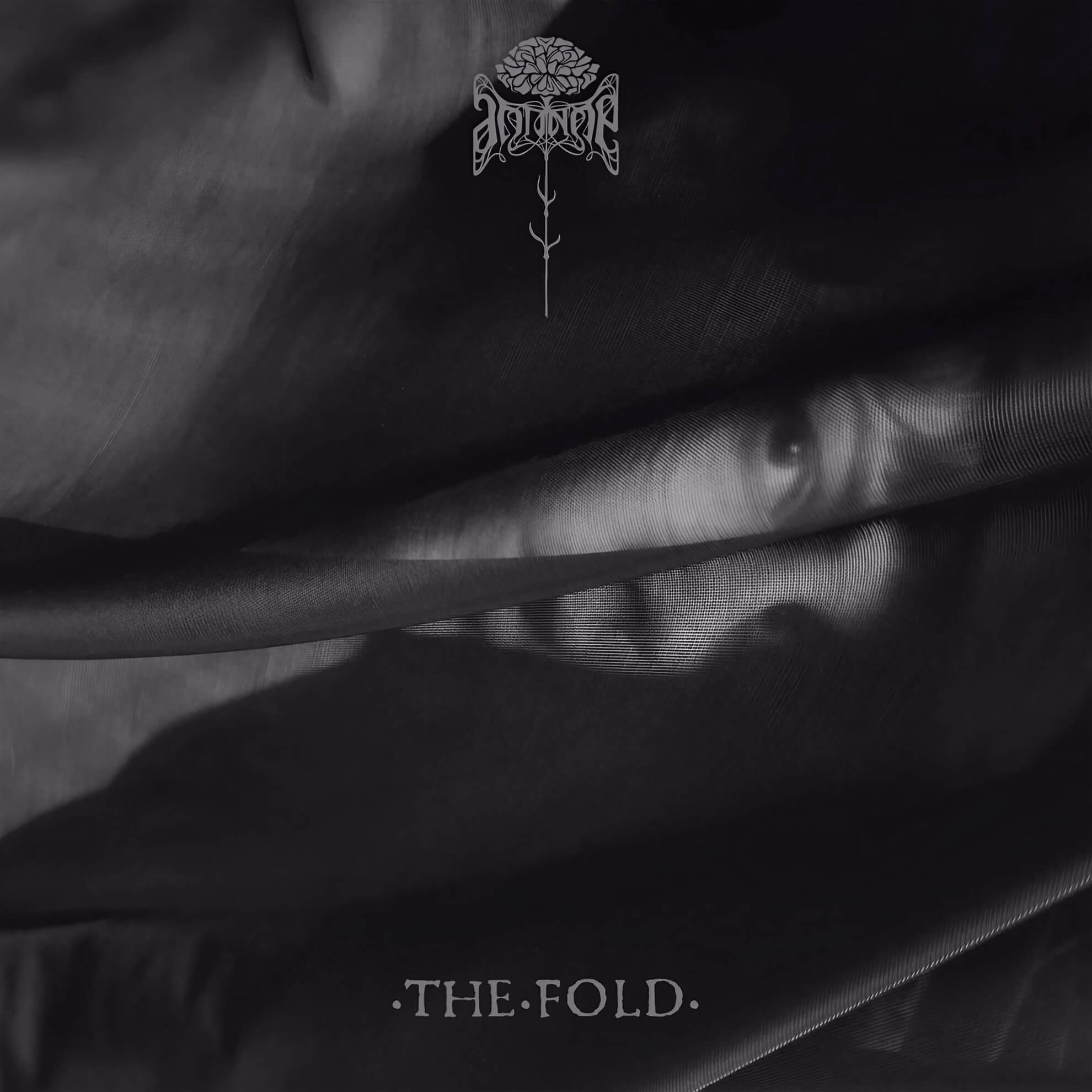 Antinoë: The Cartography of Mourning and the Psychology of ‘The Fold’ Album cover for ‘The Fold.’ A monochrome image of soft, dark fabric folds, with a faint face partially visible and a centered floral logo.