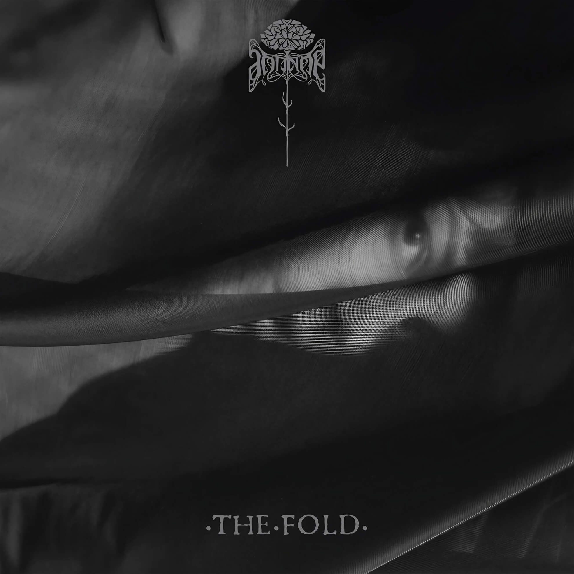 Album cover for ‘The Fold.’ A monochrome image of soft, dark fabric folds, with a faint face partially visible and a centered floral logo.