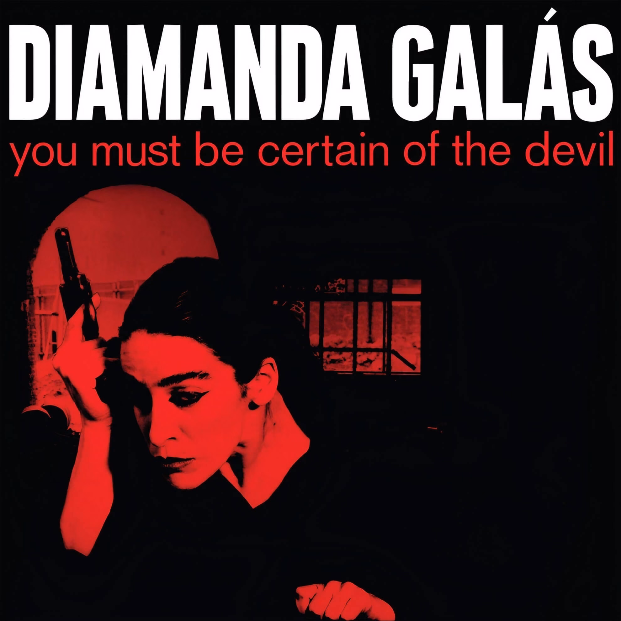 Cover for &lsquo;You Must Be Certain of the Devil.&rsquo; Red-tinted photo of Diamanda Gal&aacute;s in shadow, holding a pistol to her temple.