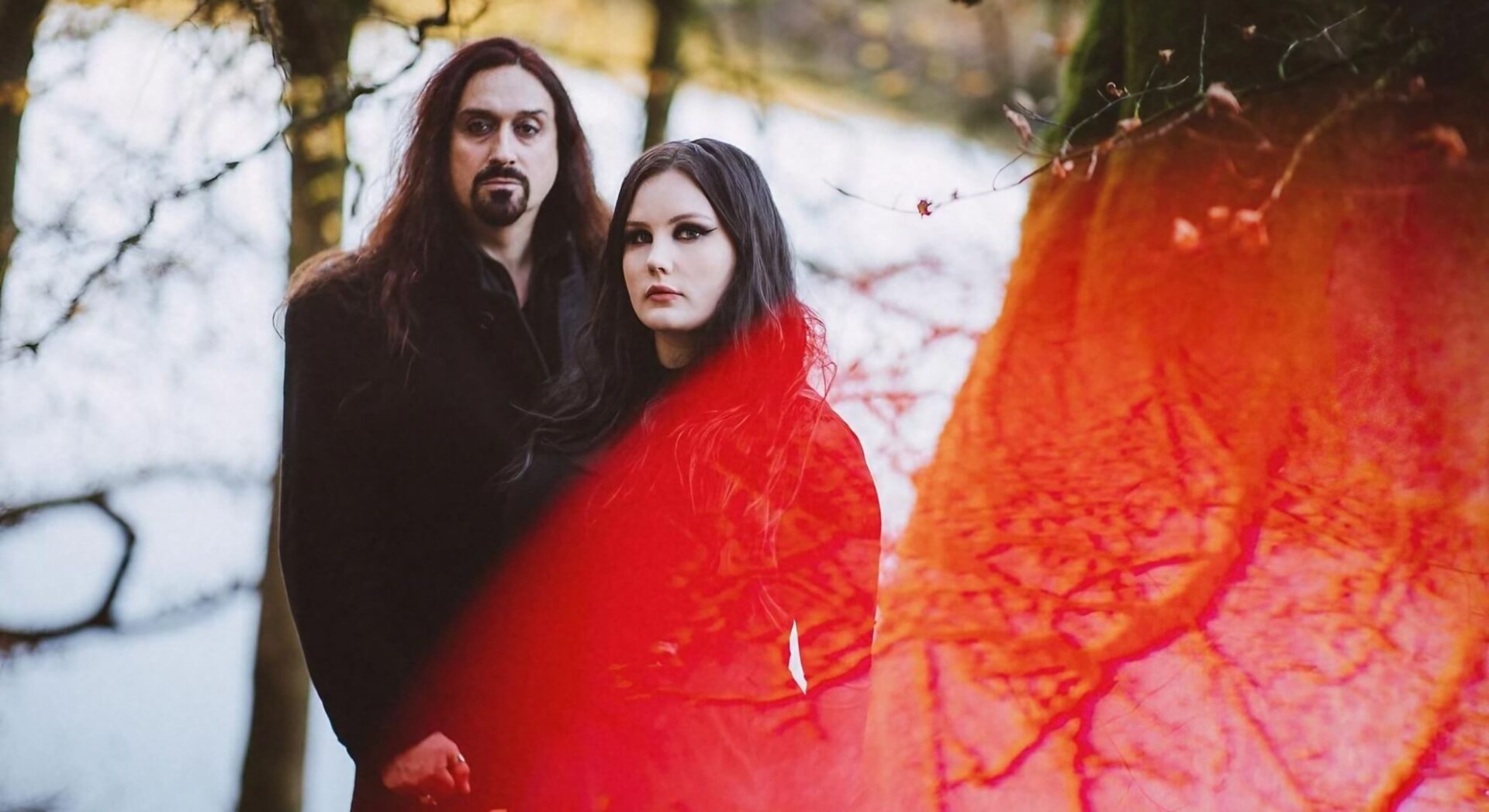 Grace Wilson and Francesco Fonte of Amnesiak stand in black clothing against a dark, misty waterfall backdrop.