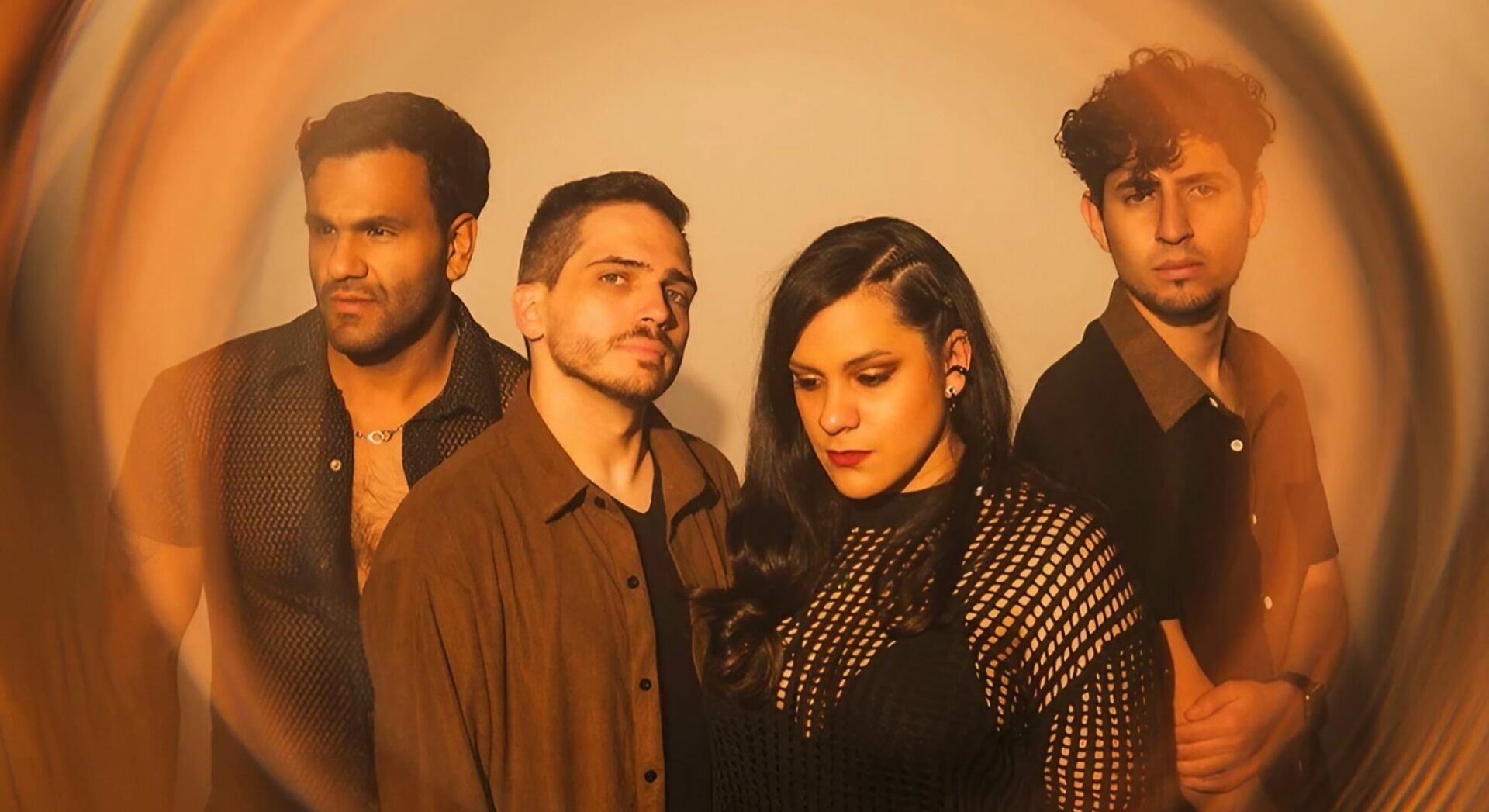 Argovia&rsquo;s four members grouped closely inside a circular lens vignette, lit in warm amber, Ani Guill&eacute;n at centre-right in a mesh top.