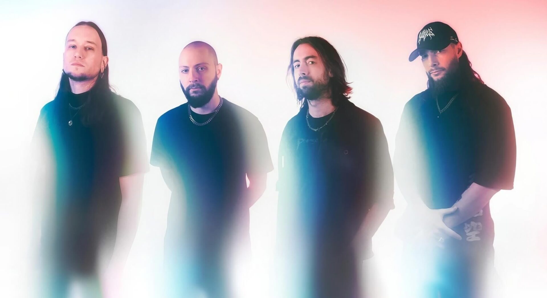 Fallujah &mdash; four members in dark clothing against a soft white-to-pink gradient in a current press portrait.