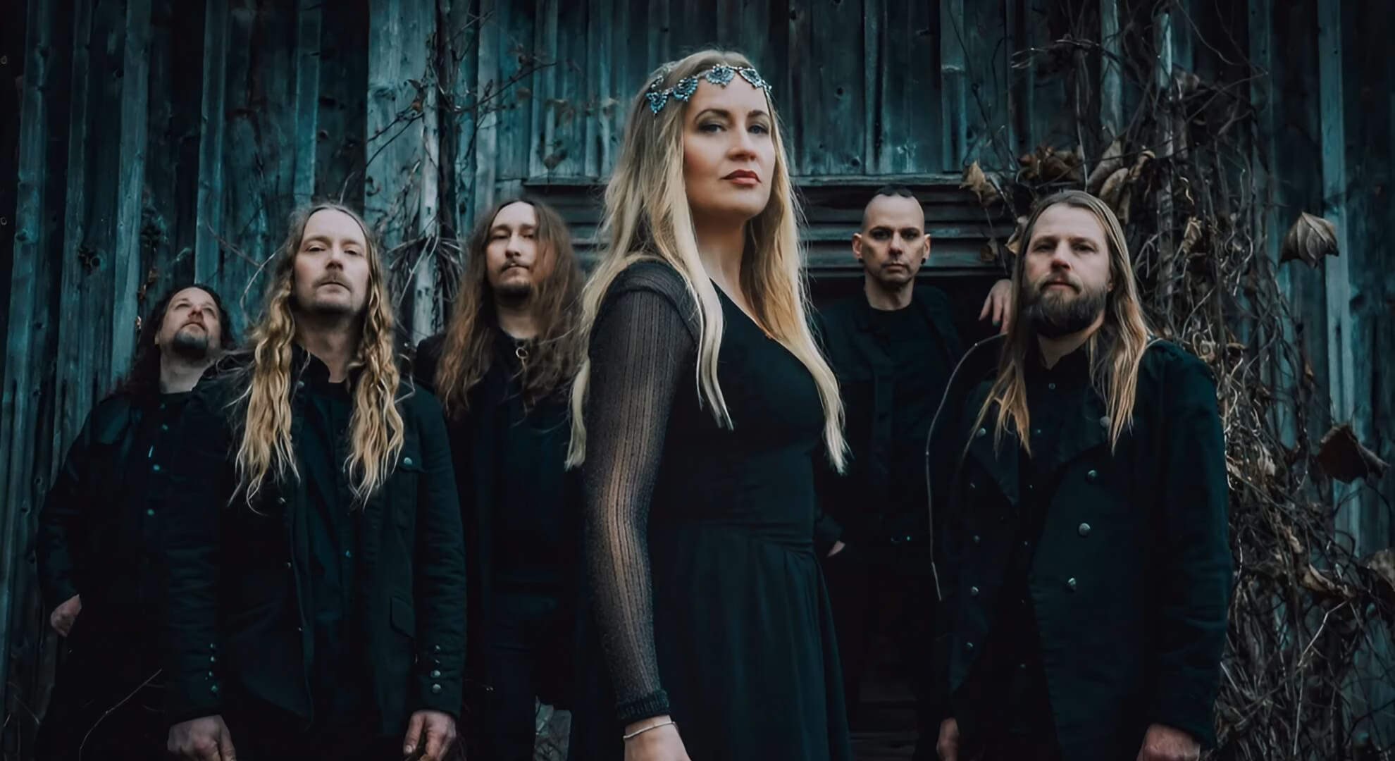 Draconian&rsquo;s five members before a weathered teal wall, Lisa Johansson centered in a jeweled headpiece.