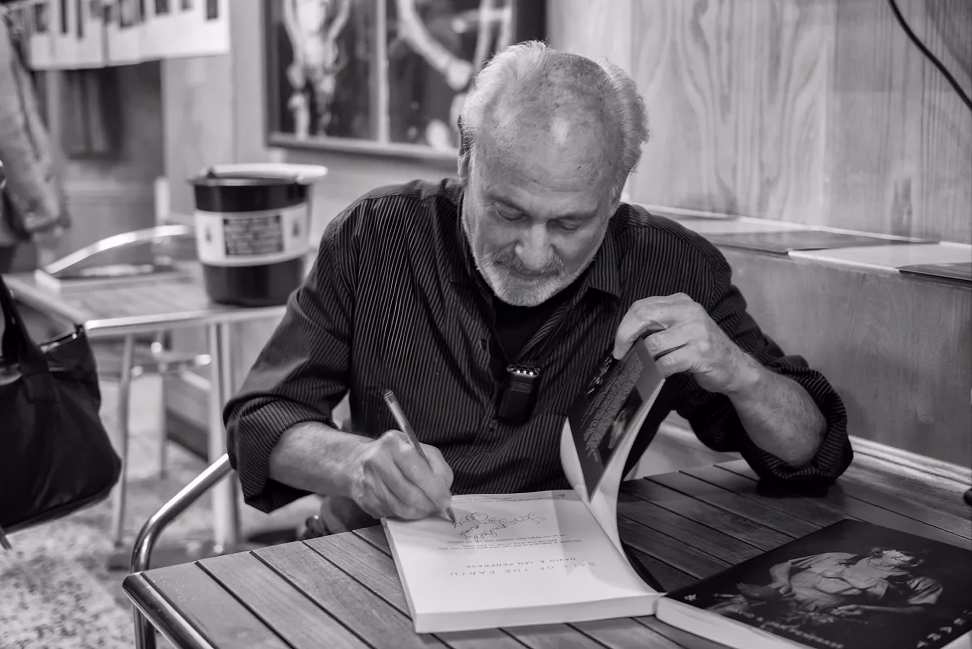 Reading the Bandaged Figure on Anathema’s ‘Serenades’ Fine-art photographer David Penprase signing one of his books at a table, in black and white.