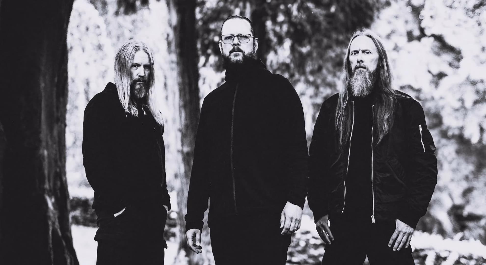 Three members of Emperor stand together outdoors, dressed in black.