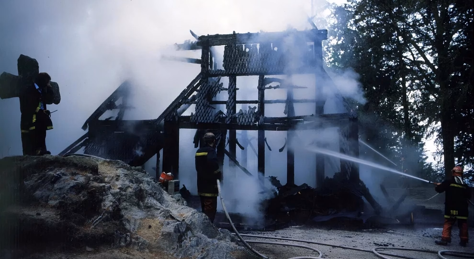 Firefighters spray water on the charred timber frame of a burned Norwegian church.