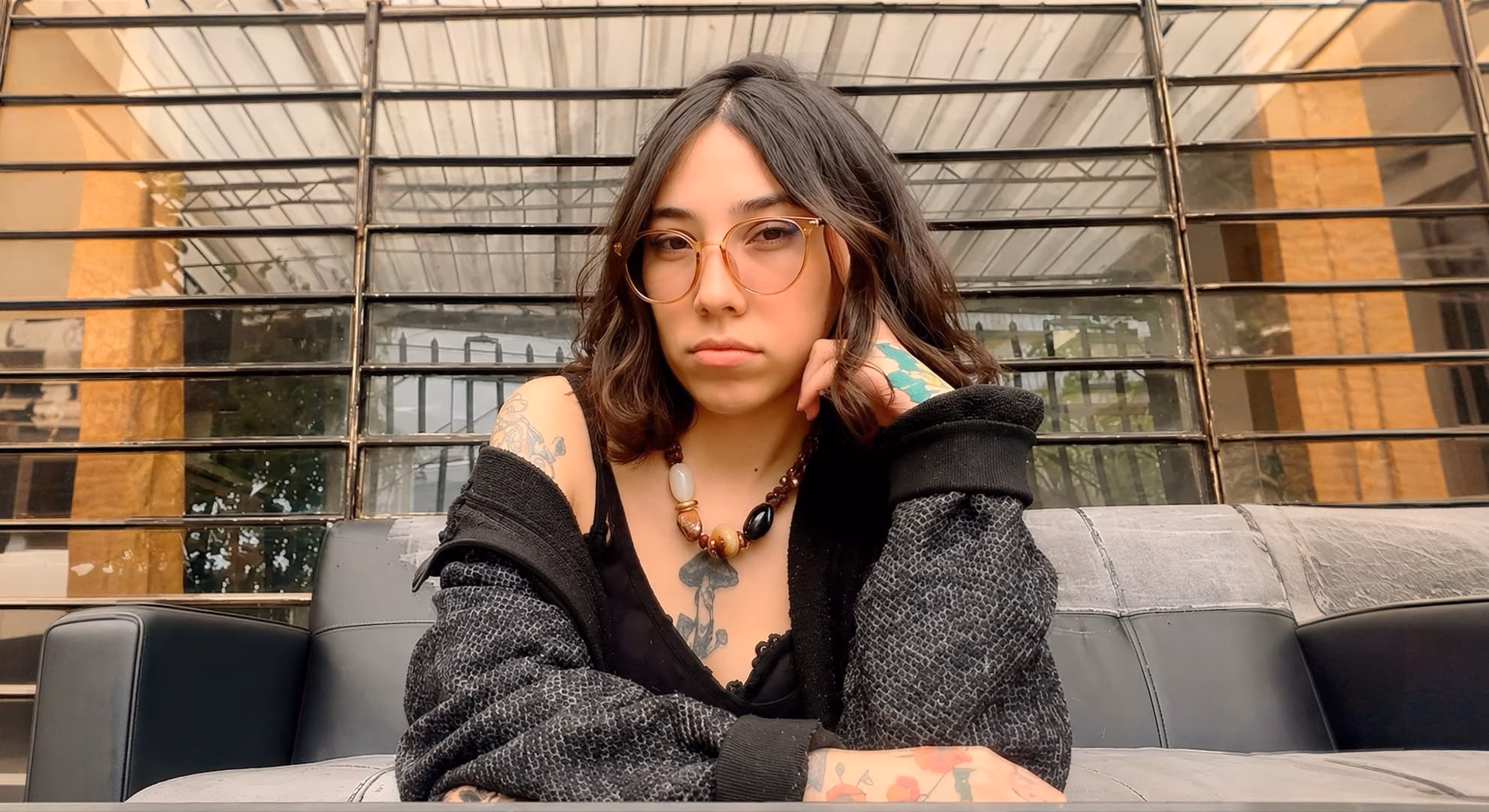Amarilla Draws Children Only Slightly Wicked Amarilla, arms crossed, pictured in a second portrait from the same rooftop sitting, tattoos and a beaded necklace visible.