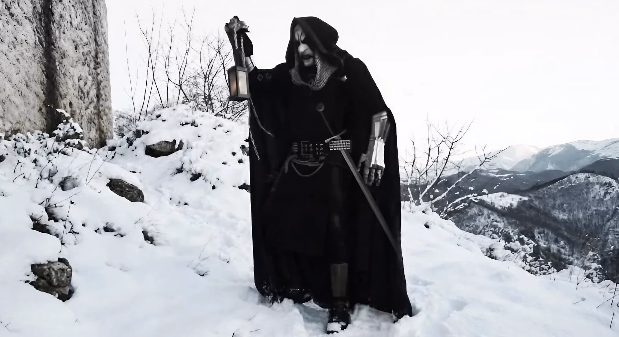 Hesperus of Hesperia beside a stone wall above snow-covered mountains, lantern and sword in hand.