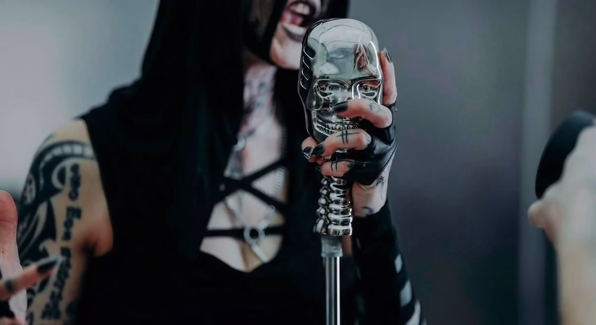 Antania Set Hecate’s Epithet to Machine Rhythm in ‘33’ A hand grips a chrome skull-shaped microphone in a still from Antania’s video for ‘33.’