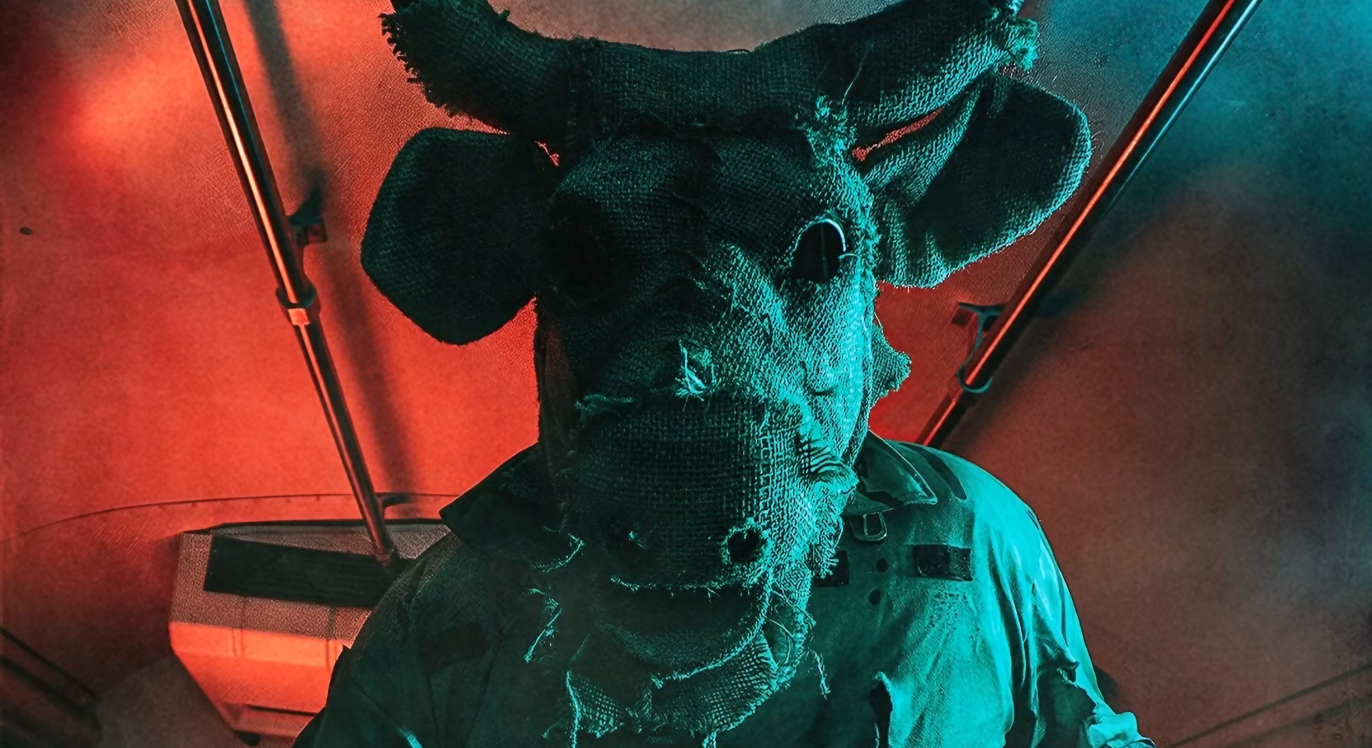 Sheboygan Haunted Asylum Returns to a Real Former Hospital A burlap-masked Sheboygan Haunted Asylum scare actor under red and teal stage lighting.